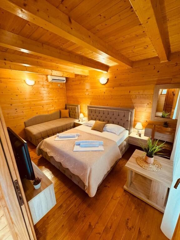 Spacious wooden room with double bed, sofa and television